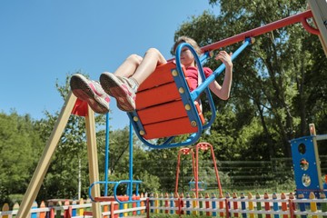 Fototapeta na wymiar Girl child riding on swing, sunny summer day