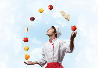 Young male chef juggles with food ingredients