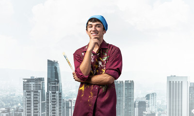 Smiling young painter artist holding paintbrush
