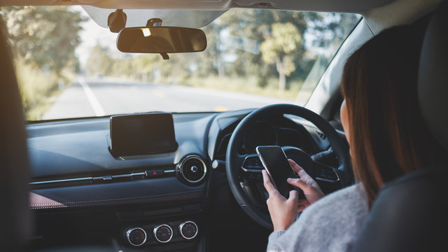 Closeup image of a woman using mobile phone while driving a car