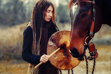 young dreadded girl with her horse and shamanic frame drum.