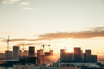 Fototapeta premium Panorama of construction at sunset. Construction of a residential complex with cranes.