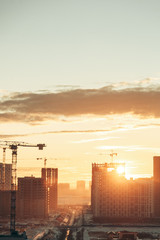 Panorama of construction at sunset. Construction of a residential complex with cranes.