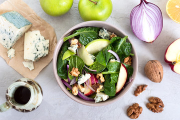 Delicious diet fitness salad with spinach, apples, red onions, blue cheese, nuts. Proper nutrition. Light concrete background. Top view.