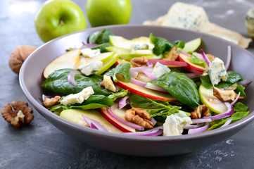 Tasty diet fitness salad with spinach, apples, red onions, blue cheese, nuts. Proper nutrition. Light concrete background
