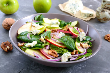 Tasty diet fitness salad with spinach, apples, red onions, blue cheese, nuts. Proper nutrition. Light concrete background