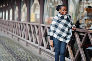 African woman in checkered cape posed outdoor.
