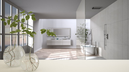 White table top or shelf with glass vase with hydroponic plant, ornament, root of plant in water, branch in vase, house plant, bathroom with bathtub in the background, interior design