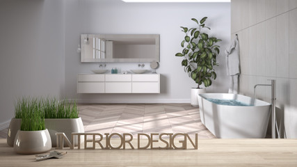 Wooden table, desk or shelf with potted grass plant, house keys and 3D letters making the words interior design, over blurred modern bathroom, project concept copy space background