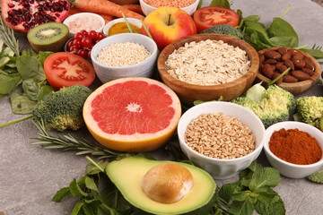 Healthy food clean eating selection: fruit, vegetable, seeds, superfood, cereals, leaf vegetable on rustic background