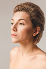 attractive blonde with short hair in the studio on a light background close-up. The concept of natural beauty, healthy skin
