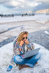 Above view of cheerful beautiful adult woman using laptop computer sitting on the ground in the city - concept of modern happy people with roaming technology - travel female and digital nomad job