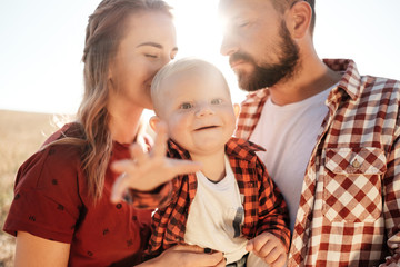 Happy Young Family Mom and Dad with Their Little Son Enjoying Summer Weekend Picnic Outside the City in the Field at Sunny Day Sunset, Vacation Time Concept