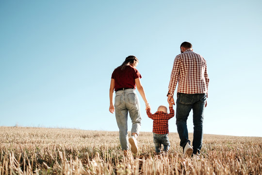 Happy Young Family Mom and Dad with Their Little Son Enjoying Summer Weekend Picnic Outside the City in the Field at Sunny Day Sunset, Vacation Time Concept