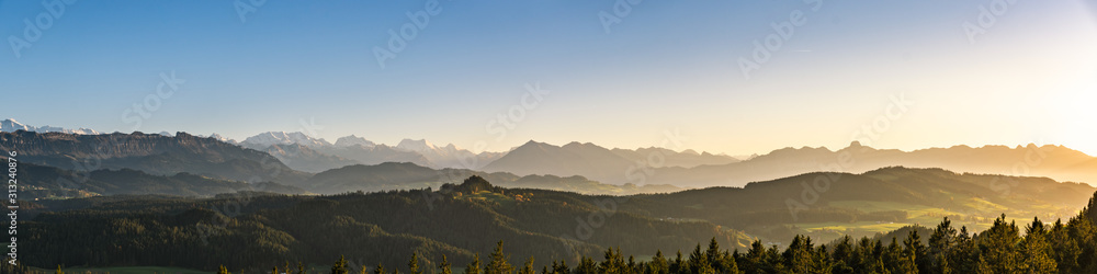 Wall mural swiss mountain range in switzerland while the valley is covered in fog during sunset, super warm lig