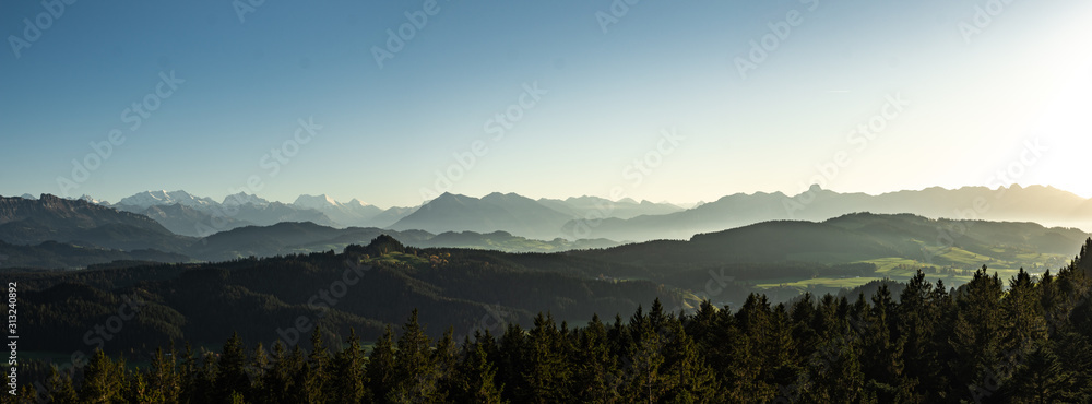Wall mural swiss mountain range in switzerland while the valley is covered in fog during sunset, super warm lig