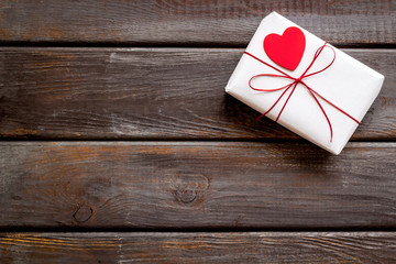 Valentine's Day gift. Present box near paper hearts on dark wooden background top-down copy space