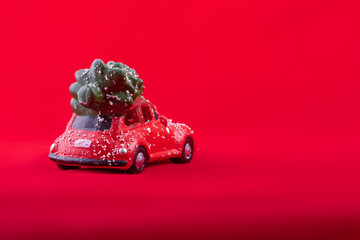 Merry Christmas card. Toy car with a Christmas tree on the roof on red background