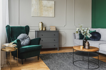 White flowers in vase on coffee table in luxury living room interior with grey couch