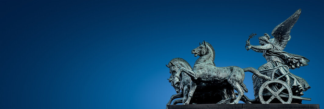 Panoramic banner of ancient bronze quadriga statue of goddess of Victory at Austrian Parliament roof in Vienna with gradient blue sky background, Austria, isolated, closeup, details