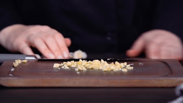 Step by step. Dicing organic garlic on wood cutting board.