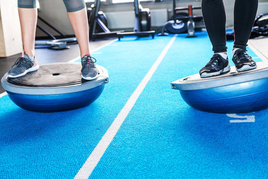 Male and female legs on bosu ball in fitness studio - Powered by Adobe