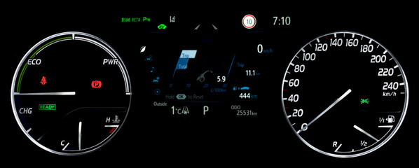 Average fuel economy consumption display between circular speedometer and power monitor. Illuminated car instrument panel with display fuel range, fuel and temperature gauge, odometer in hybrid car.