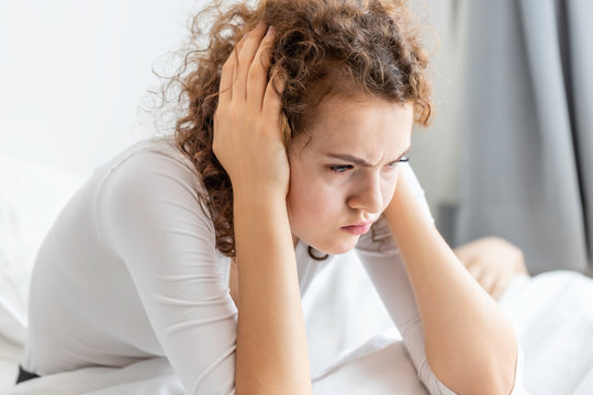 Caucasian couple in pajamas snoring and bad sleeping on the bedroom.Her blocking ears with hands.