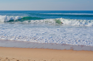 Picturesque beach in Portugal, ocean waves run ashore. Good weather for surfing.