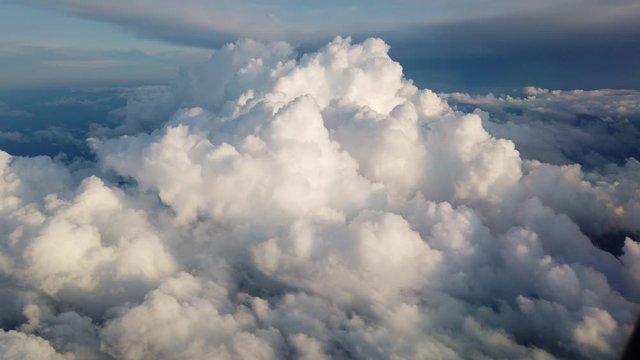 View of clouds and the solar sky from above from the plane. Clouds in the window plane. The view from the airplane. Cumulus clouds fly by, illuminated by the sun.