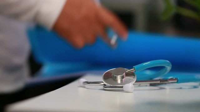 Medicine doctor hand writing prescription clipboard record information of patient in clinic, Female physician working files, have stethoscope on desk in hospital. Healthcare and medical concept. 4K