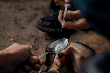 two shabby  men preparing drug injection in slums