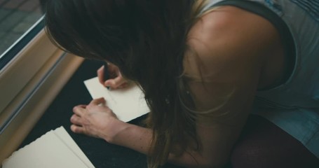 Young woman writing greeting cards on floor by french doors
