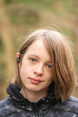 Fototapeta premium teen white female headshot. Female has blue eyes and wearing earphones, blurred background.