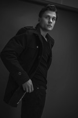 Portrait of stylish man posing on a black background. Wearing a black coat