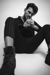 Casual fashion man in overalls and boots smoking cigarette on white background. Black and white portrait © Yevhen