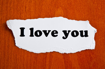 the text with words I love you on white torn paper on brown background like romantic Valentine 