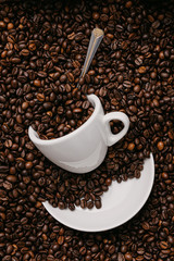 white coffee cup lies in roasted coffee beans of the highest standard