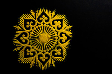 top close up view of awesome yellow rangoli art on black background with copy space. diwali concept