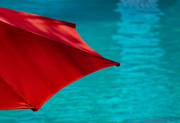 Vibrant Red Poolside Umbrella With Turquoise Sswimming Pool in the Background at a Tropical Resort Hotel