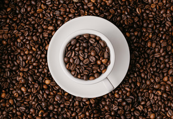 white coffee cup lies in roasted coffee beans of the highest standard