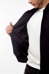 Young european man in white sweater and black pants, black bomber jacket posing on white...