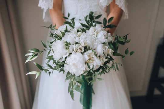 Wedding bouquet of peonies with a large stall. The bride in a white dress holds a wedding bouquet in her hands. Photography, concept.