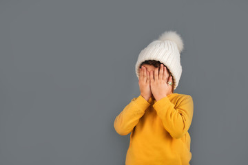 caucasian child in knitted hat closes her eyes