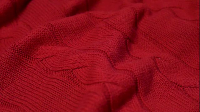 Close-up of red Burgundy knitted cotton texture fabric for textiles, bedspreads, clothing. Cozy house, detail in the interior design.