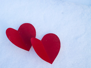 Fototapeta premium Red paper hearts on white snow as a symbol of love and warmth.