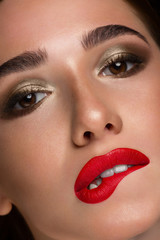 Close-up of a red-haired girl with fashionable evening make-up. Sensual plump lips with red lipstick, dark shadows on the eyelids and thick eyebrows. The fatal image of a beautiful woman.