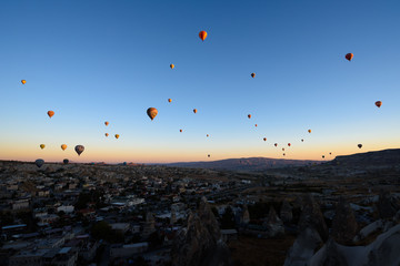 Hot air balloons flying over rocky Cappadocia landscape in Goreme, Turkey