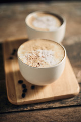 Hot coffee cup and coffee beans on wooden table..