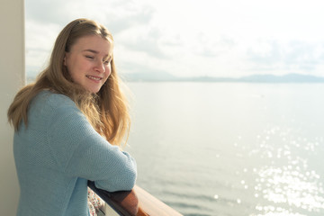 Fototapeta na wymiar Cruise ship vacation. Teenager girl relaxing on luxury cruise ship balcony. Portrait of a happy beautiful girl on a cruise ship at sunrise